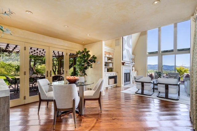 dining area with a fireplace, french doors, hardwood / wood-style floors, recessed lighting, and a mountain view