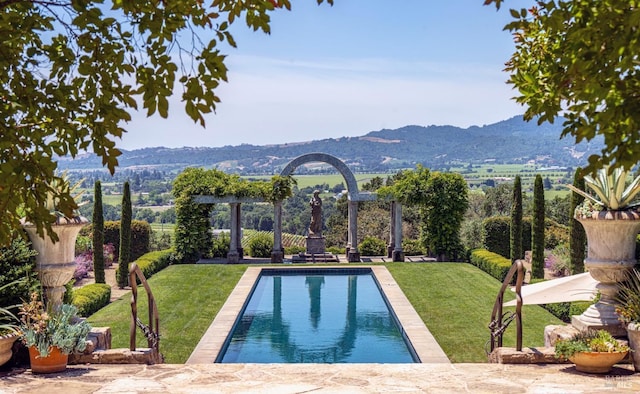 view of swimming pool featuring a fenced in pool, a mountain view, and a yard
