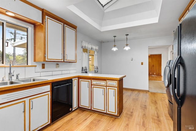 kitchen featuring pendant lighting, a sink, black appliances, a peninsula, and light wood-style flooring