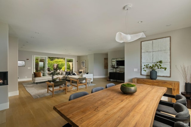 dining area featuring a multi sided fireplace, recessed lighting, baseboards, and wood finished floors