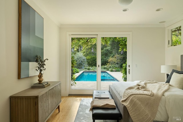 bedroom with light wood-style floors, crown molding, and access to exterior
