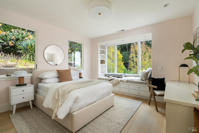 bedroom with light wood-style floors and visible vents