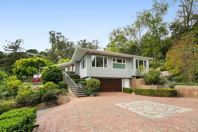 view of front of home featuring stairs, an attached garage, stucco siding, and decorative driveway