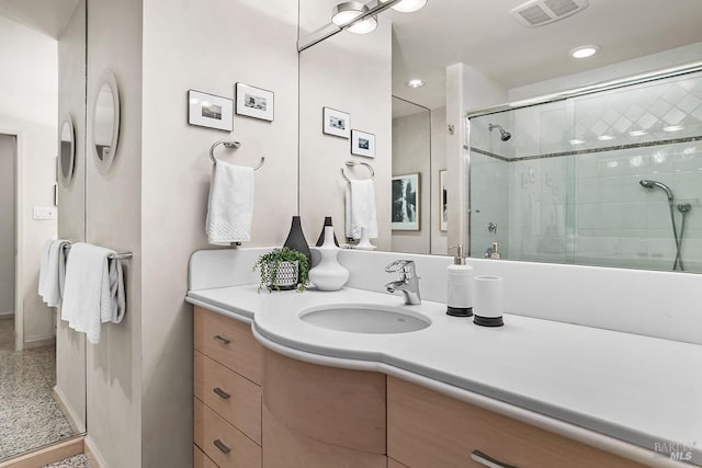 full bathroom with baseboards, visible vents, a shower stall, and vanity