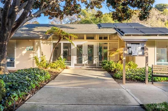 exterior space featuring french doors, solar panels, and stucco siding