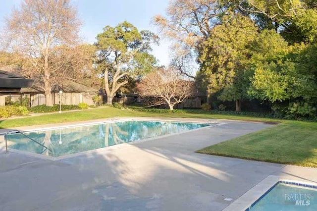 view of swimming pool featuring a fenced in pool, fence, a patio, and a lawn