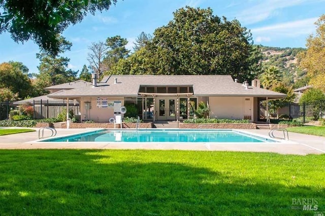 view of swimming pool with a yard, fence, a fenced in pool, and french doors