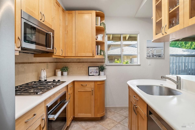 kitchen with light countertops, appliances with stainless steel finishes, decorative backsplash, and a sink