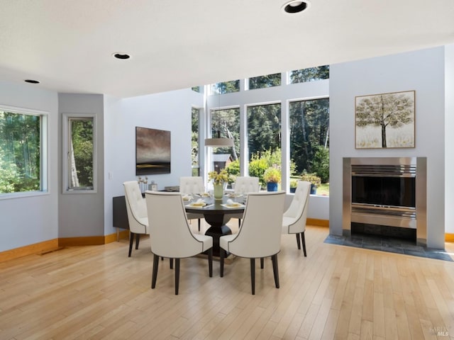 dining space with recessed lighting, baseboards, a glass covered fireplace, and hardwood / wood-style flooring