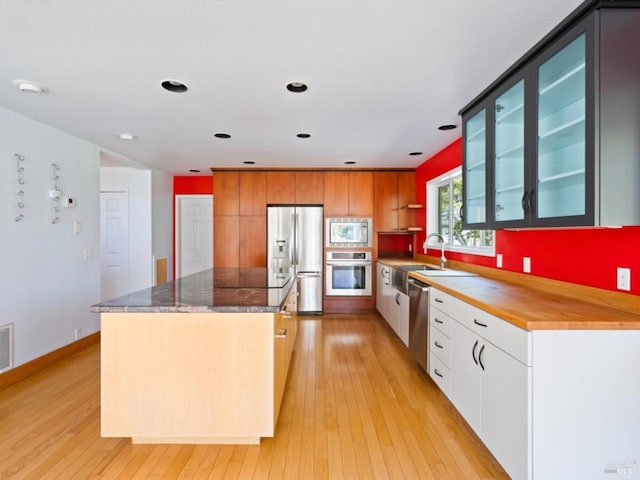 kitchen featuring a kitchen island, appliances with stainless steel finishes, a sink, and light wood-style flooring