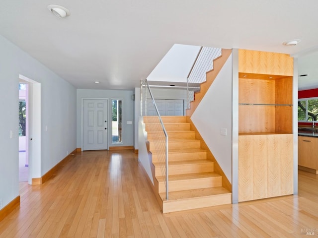 entryway with stairway, baseboards, and light wood-style flooring