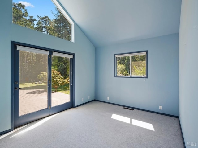 carpeted spare room featuring baseboards, visible vents, and high vaulted ceiling