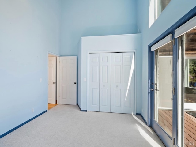 unfurnished bedroom featuring carpet floors, a high ceiling, and multiple windows