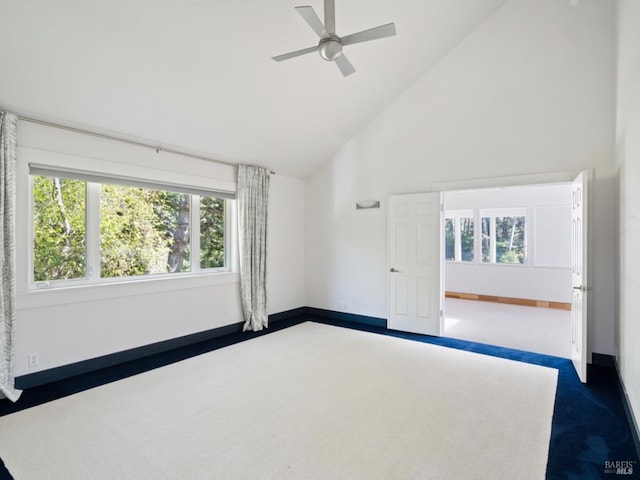 empty room with baseboards, a ceiling fan, high vaulted ceiling, and dark carpet