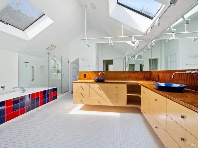 full bathroom with double vanity, a shower stall, a sink, and vaulted ceiling with skylight