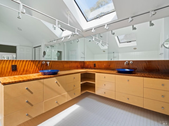 kitchen with track lighting, a sink, wood counters, and lofted ceiling with skylight