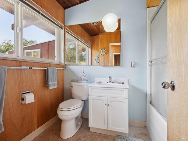 bathroom with toilet, baseboards, shower / bath combination with glass door, and vanity
