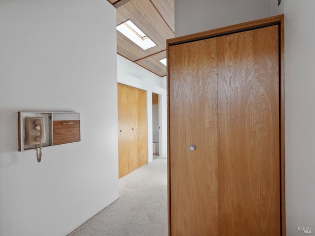 hallway featuring carpet flooring and lofted ceiling with skylight