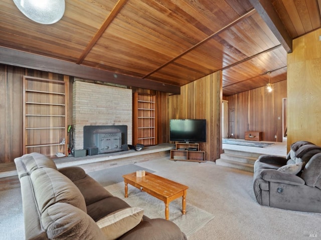 living room featuring carpet flooring, wood walls, a large fireplace, built in shelves, and wood ceiling