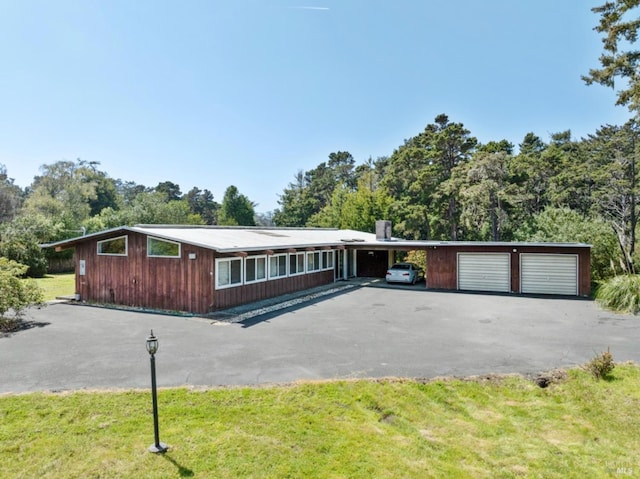 ranch-style home with a detached garage, driveway, and a front yard