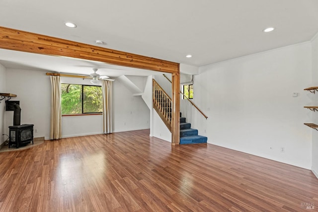unfurnished living room with recessed lighting, a wood stove, stairs, and wood finished floors