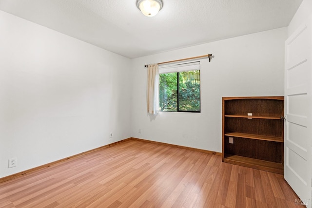 unfurnished room featuring baseboards and light wood-style floors