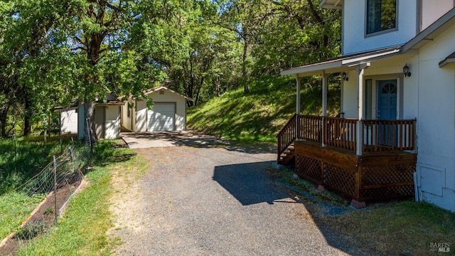 view of yard with covered porch, an outbuilding, and gravel driveway
