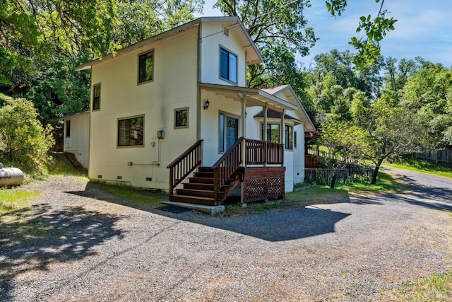 rear view of house with crawl space, driveway, and fence