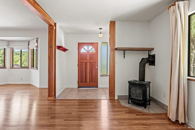 entrance foyer with baseboards, wood finished floors, and a wood stove