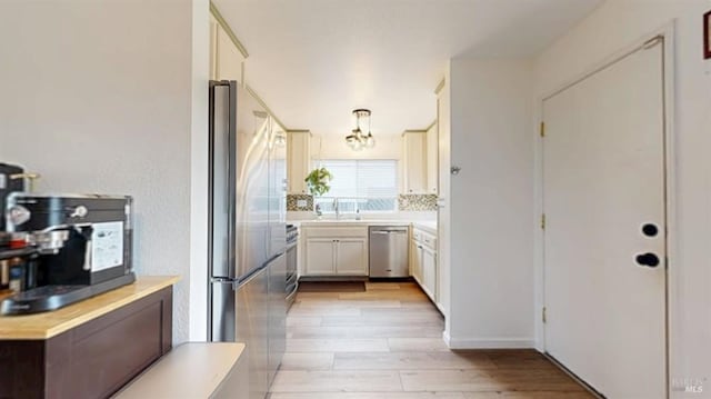 kitchen with light countertops, a notable chandelier, appliances with stainless steel finishes, and light wood finished floors