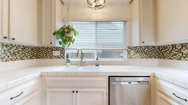 kitchen featuring a sink, decorative backsplash, stainless steel dishwasher, and white cabinets