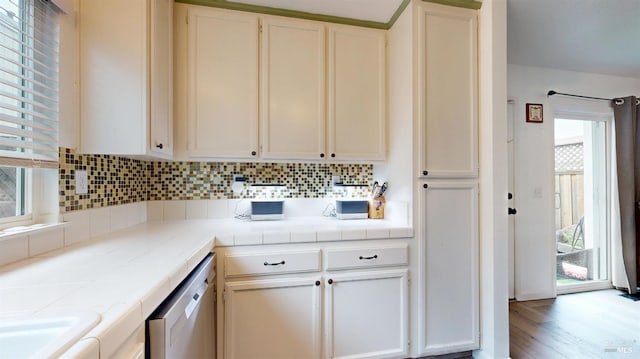 kitchen with white cabinets, tasteful backsplash, dishwasher, tile counters, and light wood-type flooring