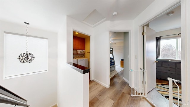 corridor with baseboards, washer and clothes dryer, and light wood-type flooring