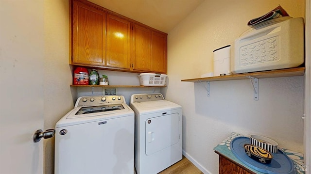 clothes washing area featuring baseboards, light wood-style flooring, cabinet space, and washer and dryer