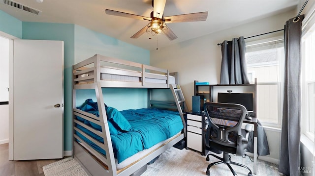 bedroom featuring visible vents, a ceiling fan, baseboards, and wood finished floors