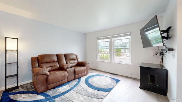 living room featuring visible vents, light wood-style floors, and baseboards