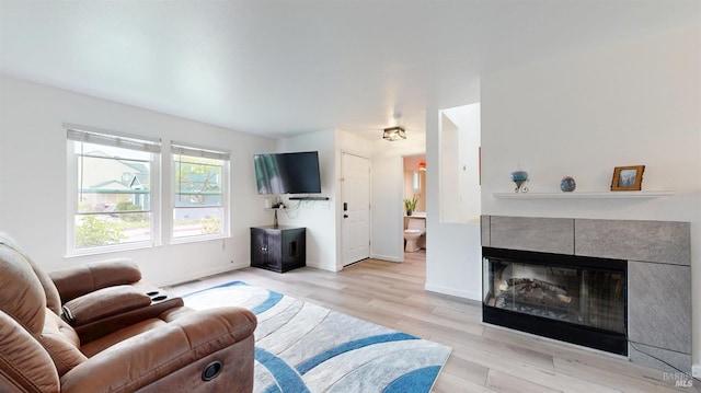 living area with baseboards, wood finished floors, and a fireplace