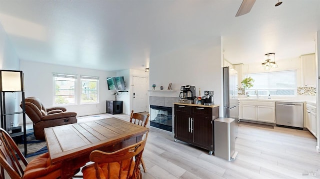 kitchen with stainless steel dishwasher, open floor plan, light wood-type flooring, light countertops, and ceiling fan with notable chandelier