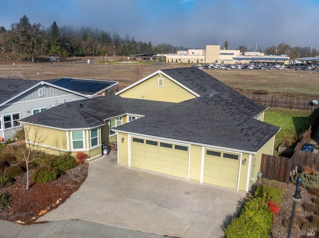 view of front facade with a garage, fence, driveway, and a shingled roof