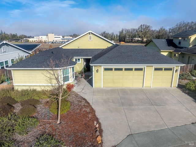 ranch-style house featuring a garage, a shingled roof, and concrete driveway