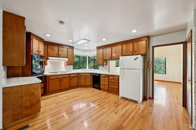 kitchen with brown cabinetry, tasteful backsplash, and black appliances