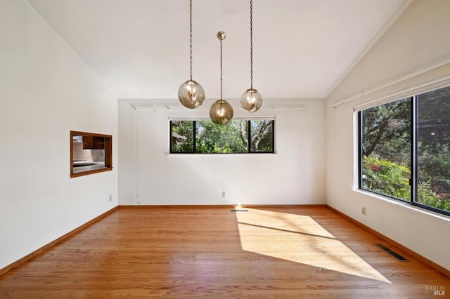 empty room featuring baseboards, vaulted ceiling, visible vents, and wood finished floors