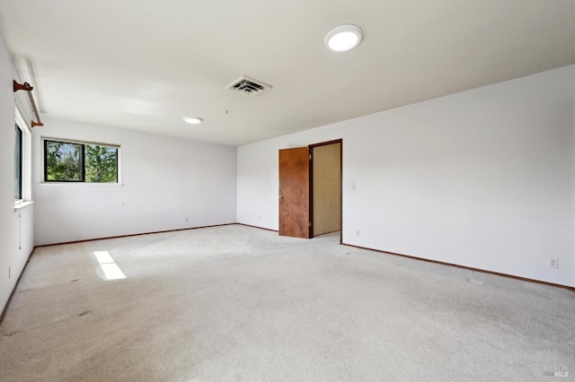 spare room with baseboards, visible vents, and light colored carpet