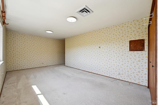 carpeted spare room featuring visible vents and wallpapered walls