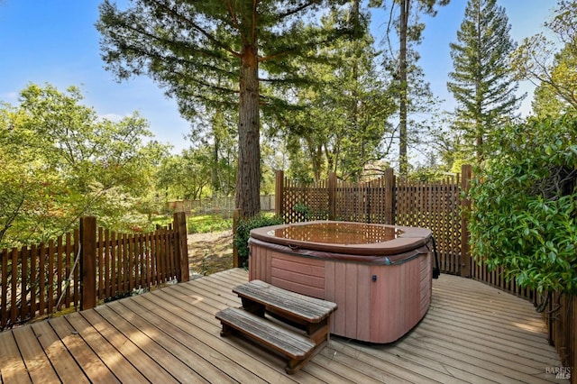 deck featuring a hot tub and a fenced backyard