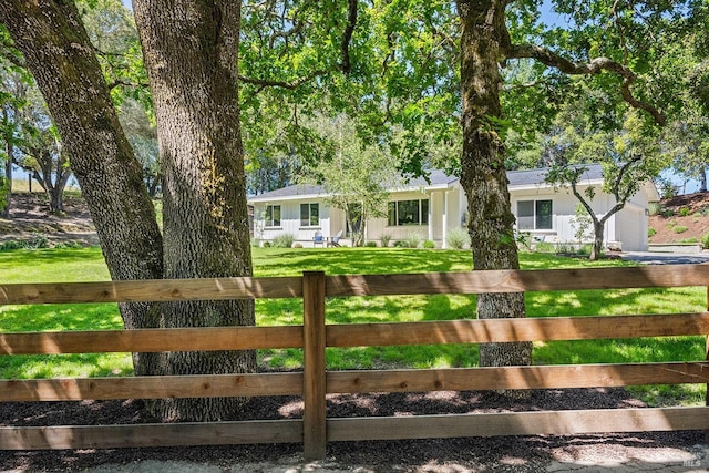 ranch-style house with driveway, a fenced front yard, and a front yard