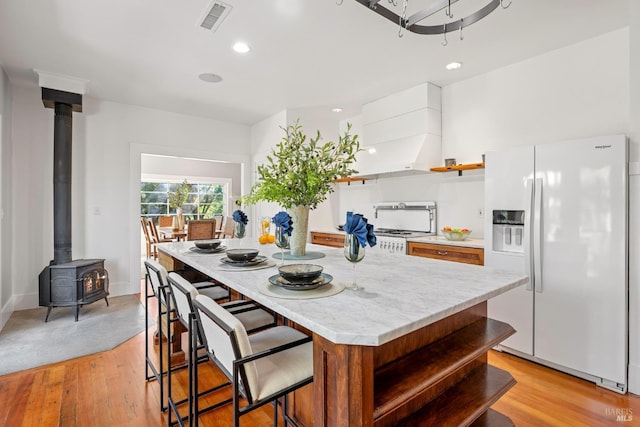2855 Old Gravenstein Hwy, Sebastopol, CA 95472 - kitchen with white fridge with ice dispenser, open shelves, a wood stove, a center island, and light countertops