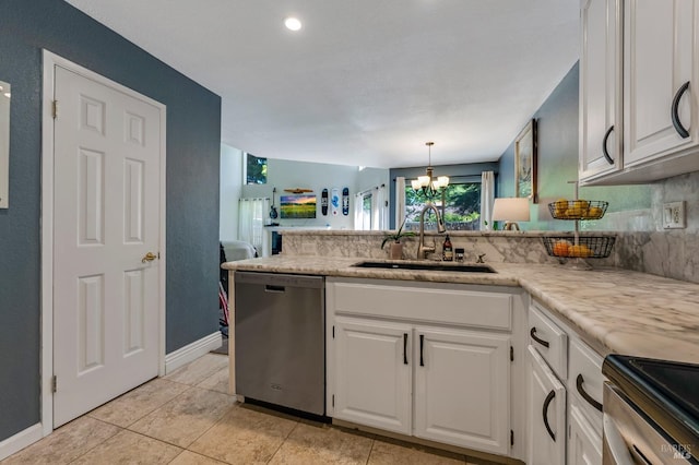 kitchen with appliances with stainless steel finishes, a sink, white cabinets, a peninsula, and a chandelier