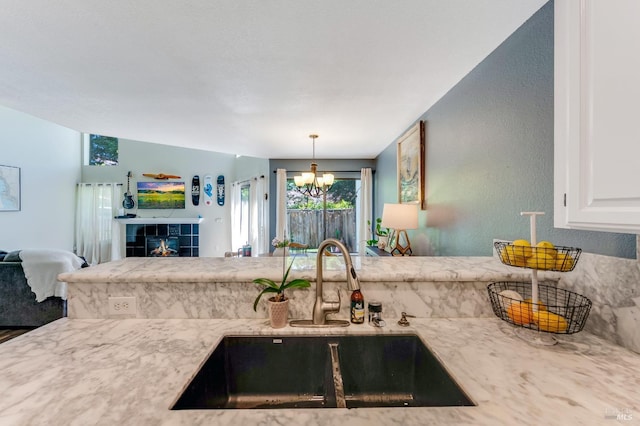 kitchen featuring a sink, a chandelier, white cabinetry, decorative light fixtures, and open floor plan