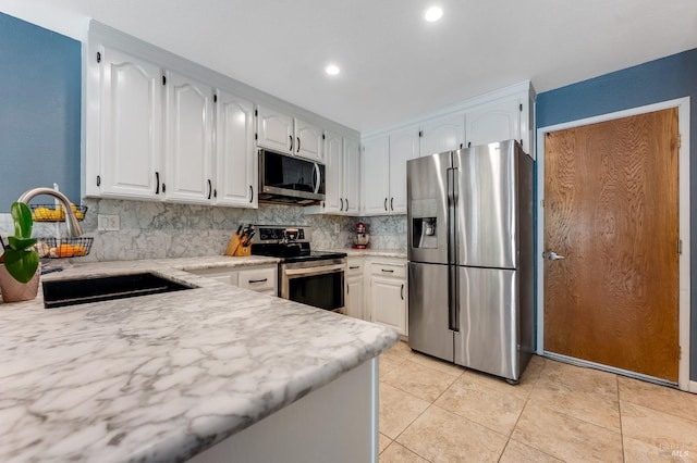 kitchen featuring decorative backsplash, recessed lighting, white cabinets, a sink, and appliances with stainless steel finishes